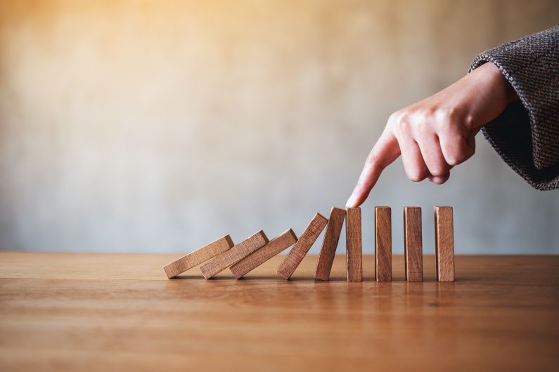 mão derrubando trilha de dominó